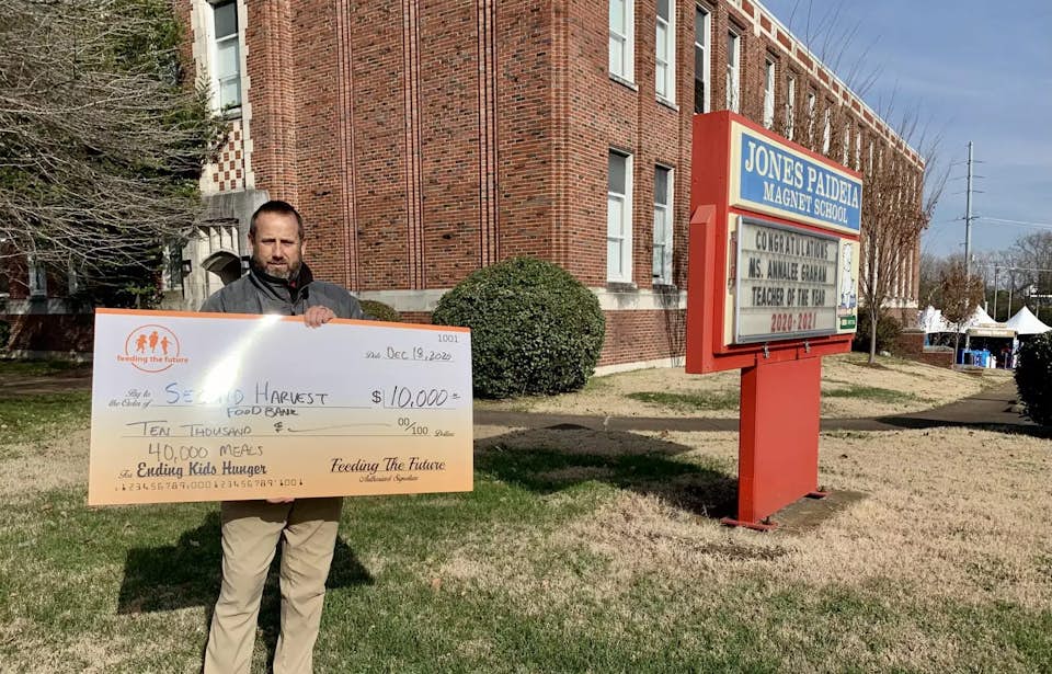 Man holding check outside of school